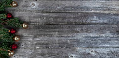 Gerçek köknar ağacı dallarının sol sınırı artı kırsal ahşap arka planda altın ve kırmızı top süslemeleri Mutlu Noeller ya da mutlu noeller bayramı kutlaması konsepti için  