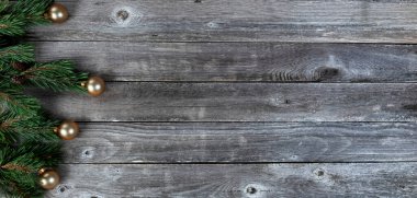 Köknar ağacı dallarının sol sınırı ve ahşap kaplamalı altın top süslemeleri mutlu bir Noel ya da yeni yıl bayramı kutlaması konsepti için.  