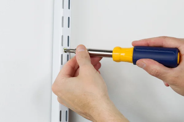 Montage von Metallbügeln an der Wand mit Handschraubendreher — Stockfoto