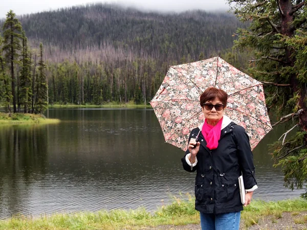 Aktive Seniorin bei Regen draußen — Stockfoto