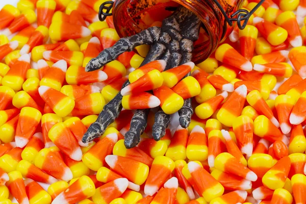 Scary skeleton hand coming out jar giving candy corn — Stock Photo, Image