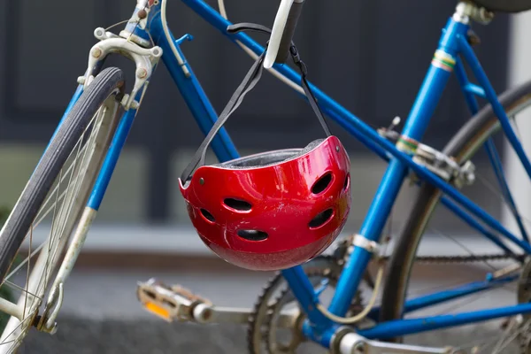 Bright red bicycle helmet hanging from handle bars