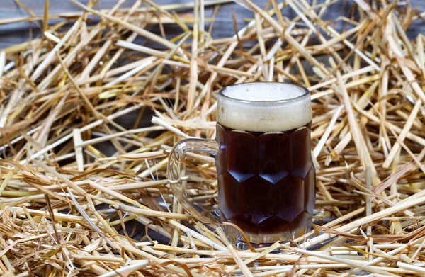 Europese donker bier in stein op stro en hout — Stockfoto