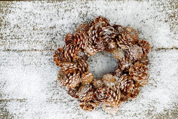 Ghirlanda di pino naturale su neve e legno — Foto Stock