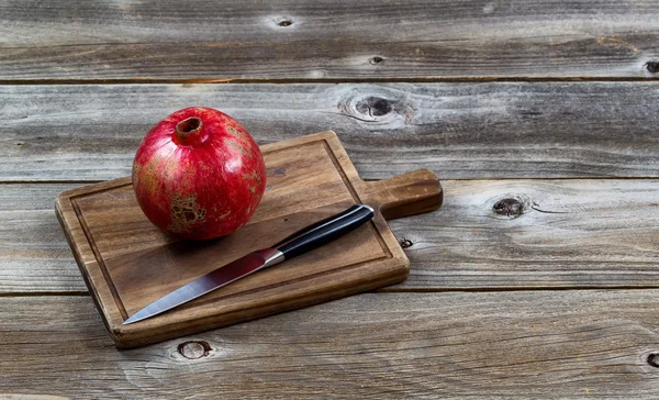 Whole ripe pomegranate fruit with knife on board — Stock Photo, Image