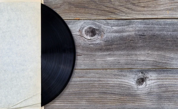 Original vinyl music record in paper holder on aged wood — Stock Photo, Image