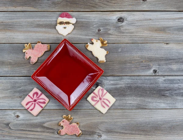 Christmas Cookies decorations around red plate on wood — Stock Photo, Image