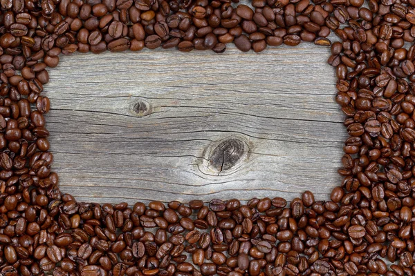 Border of freshly roasted coffee beans on aged wood — Stock Photo, Image