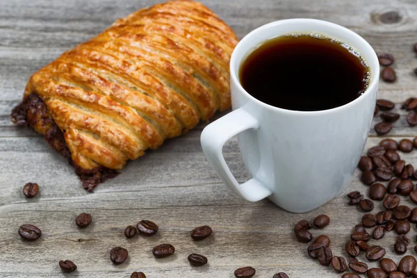 Dark coffee with large pastry on rustic wood — Stock Photo, Image