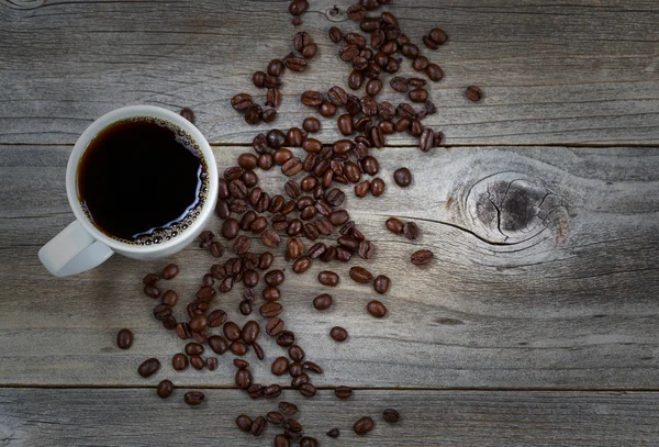 Dunkler Kaffee und Bohnen auf rustikalem Holz mit leichtem Vignettenrand — Stockfoto