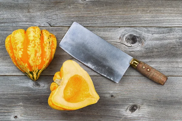 Zucca appena tagliata con coltello grande su legno rustico — Foto Stock