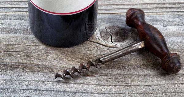Leeftijd kurkentrekker en fles wijn op rustieke hout — Stockfoto