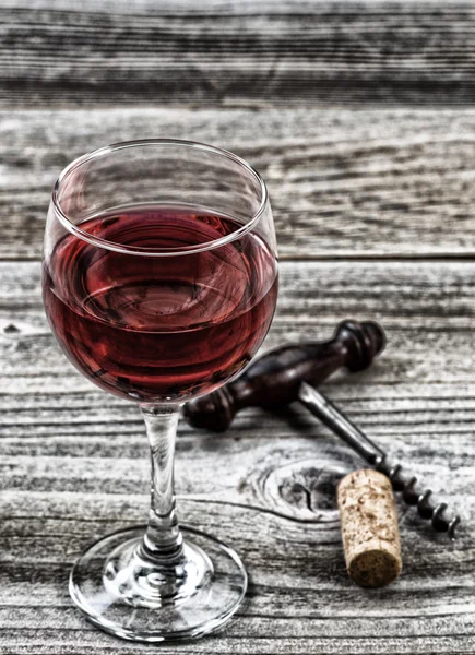 Vintage corkscrew with red wine in glass