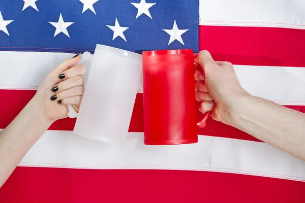 Hands holding drinking mugs with USA flag in background — Stock Photo, Image