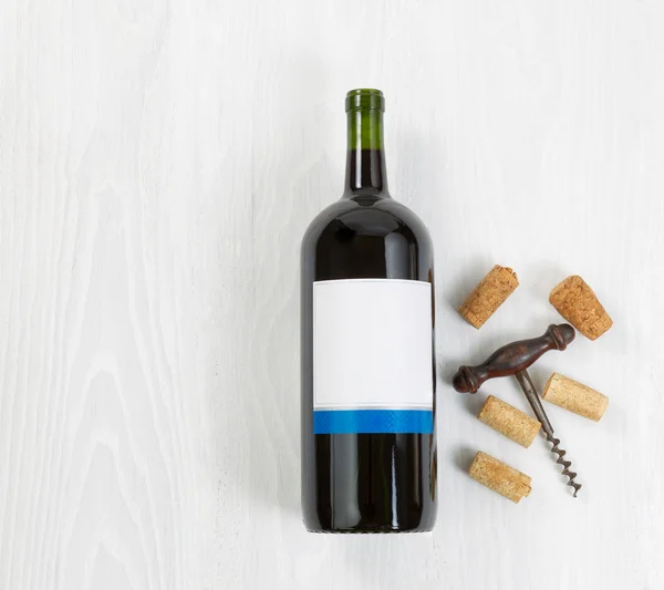 Large bottle of red wine with an antique corkscrew and old corks — Stock Photo, Image