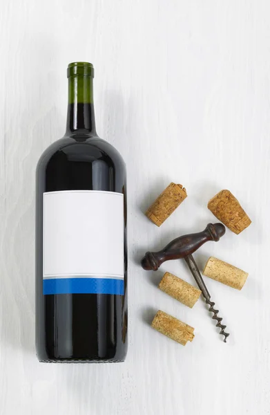 Unopened large bottle of red wine with an antique corkscrew and — Stock Photo, Image