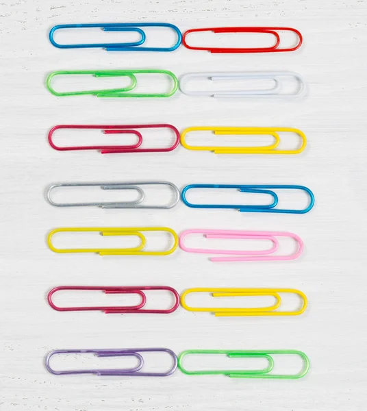 Colorful paper clips organized on white wood — Stock Photo, Image