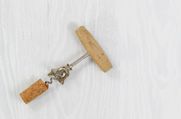 Nahaufnahme eines Korkenziehers mit aufgesetztem Korken auf weißem Holz — Stockfoto