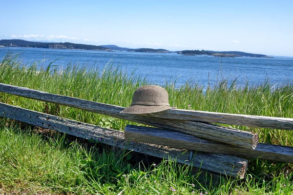 Cerca de trilho dividido com chapéu na frente da água — Fotografia de Stock