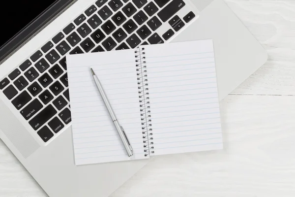 Φορητό υπολογιστή με κενό σημειωματάριο και στυλό πάνω σε λευκή επιφάνεια εργασίας — Φωτογραφία Αρχείου