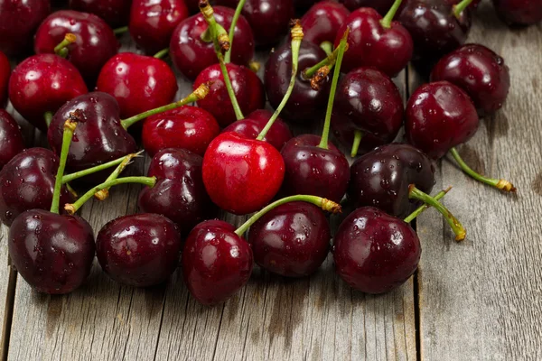 Cerezas negras enteras maduras sobre madera rústica lista para comer — Foto de Stock