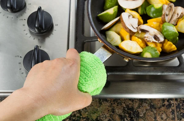 Holding frying pan with green cloth — Stock Photo, Image