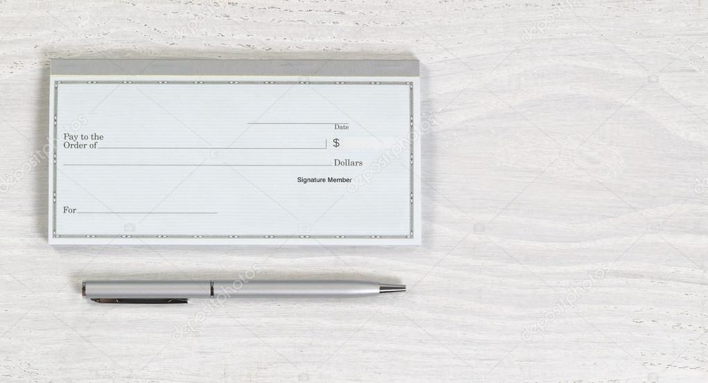 Blank checkbook and silver pen on white desktop