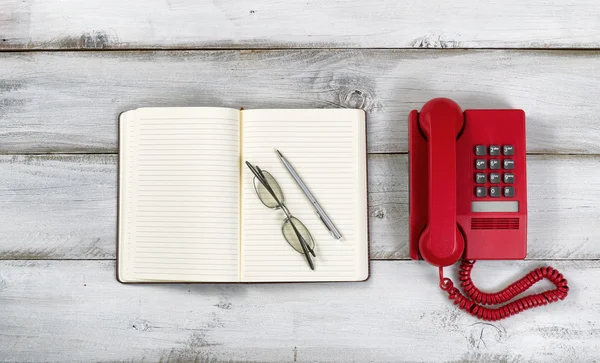 Vintage red phone and notepad with pen and reading glasses on ru — 图库照片