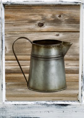 View of vintage coffee pot thru old window on rustic wooden boar