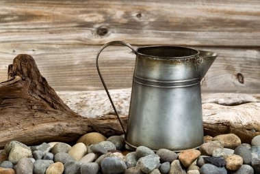 Vintage coffee pot on stone fire pit with driftwood in backgroun