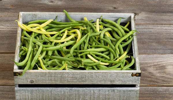 Green and yellow beans in old crate on rustic wooden boards — Stok fotoğraf