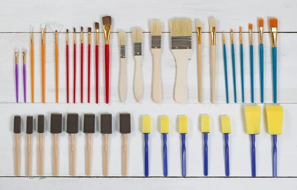 Organized new paintbrushes and applicators on white wooden board — Stock Photo, Image