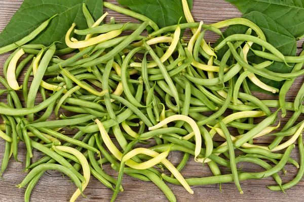 Hög med gröna och gula bönor på rustika plankor — Stockfoto