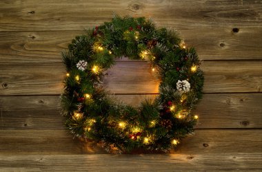 Rustik ahşap kurullarında beyaz ışıklı Noel çelenk