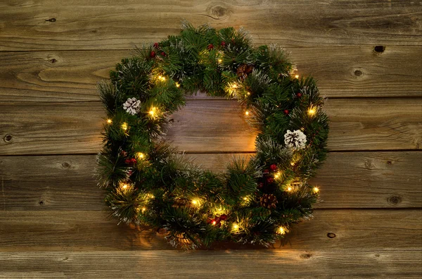Christmas wreath with white lights on rustic wooden boards