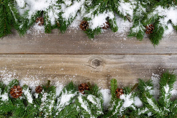 Kerstmis grens met sneeuw bedekt takken van rustieke houten boa — Stockfoto