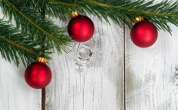 Grand fir branch with three red ornaments on rustic white wooden — Stock Photo, Image