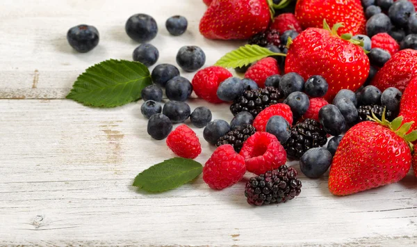 Frisch gepflückte Beeren auf rustikalen weißen Holzbrettern — Stockfoto