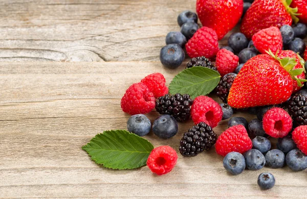 Frisch gepflückte Beeren auf rustikalen Holzbrettern — Stockfoto