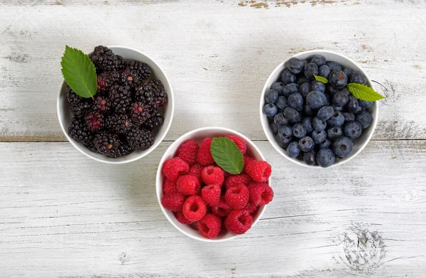 Bowls filled with freshly picked berries on rustic white wooden — Stock Photo, Image