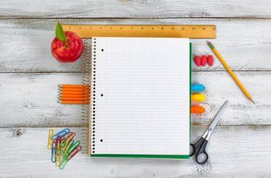 Beyaz ahşap masa üzerinde apple ile temel okul malzemeleri 