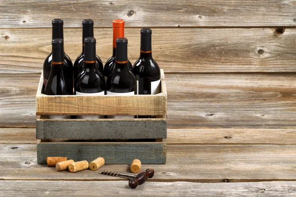 Bottiglie di vino rosso in cassa di legno su tavole di legno rustiche — Foto Stock