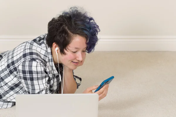 Glimlachend tienermeisje met behulp van haar mobiele telefoon en luisteren naar muziek — Stockfoto