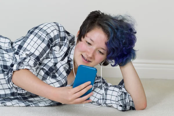 Tienermeisje met behulp van haar mobiele telefoon en luisteren naar muziek thuis — Stockfoto