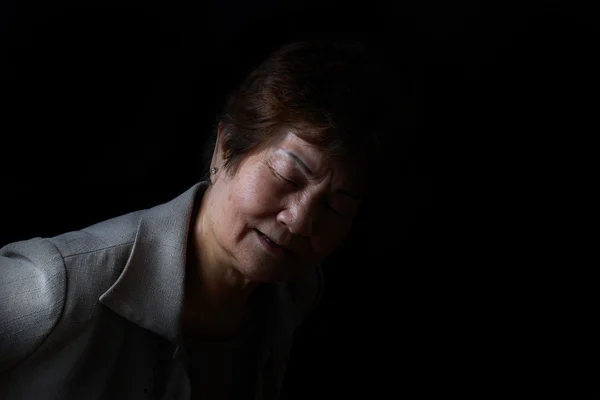 Senior woman showing back pain on black background — Stock Photo, Image