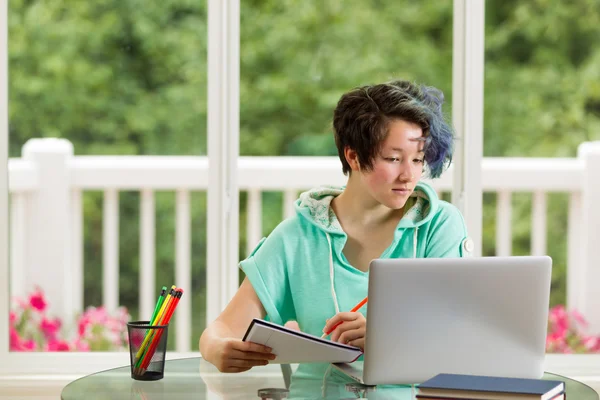 Avslappnad tonårig flicka gör hennes skolarbete hemma — Stockfoto