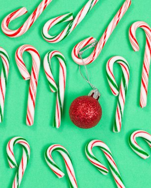 Collection of colorful candy canes and ornament on green backgro