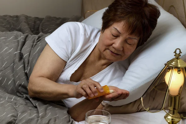 Senior mulher tomando seu remédio à noite devido à doença — Fotografia de Stock