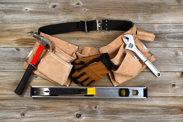 Leather tool belt with tools on rustic wooden boards — Stock Photo, Image