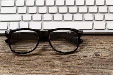 Hipster okuma gözlüğü ile klavye rustik ahşap masaüstü